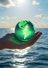 Hand holding glowing green globe over ocean at sunset, symbolizing marine conservation and sustainability