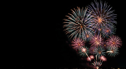 Fototapeta premium A dazzling display of colorful fireworks bursts across the night sky, illuminating the darkness with a symphony of light and celebration.