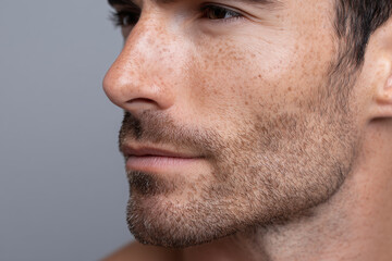 Fototapeta premium Close up macro shot of man cheek and jawline showing natural skin texture with visible pores, light facial hair, and freckles, highlighting hydrated and healthy skin appearance