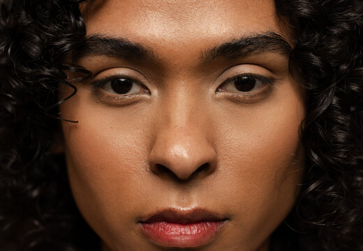 Non-binary person posing under soft directional lighting in portrait studio showcasing skin texture