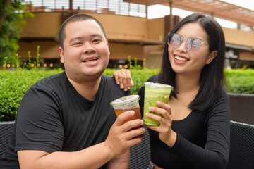 Happy couple sitting together in outdoors cafe restaurant during summer