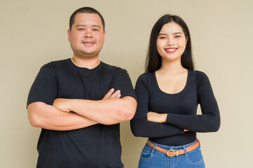 Portrait of young couple against plain wall background