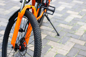 A detailed close up photograph of a bicycle wheel sitting on a brick sidewalk