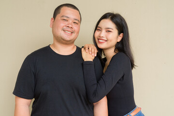 Portrait of young couple against plain wall background