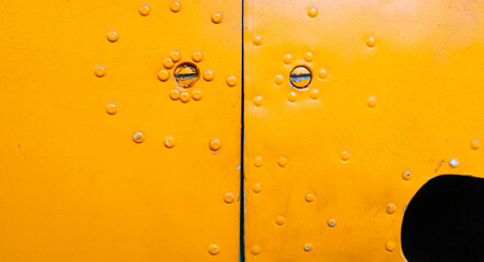 Close-up of riveted yellow aircraft fuselage with visible screws and gap