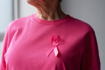 Senior woman wearing pink ribbon supporting breast cancer awareness