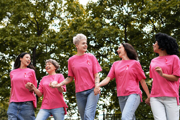 Women holding hands and wearing pink ribbons are walking for breast cancer awareness