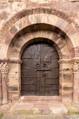 Old wooden door with metal hinges in romanesque stone arch