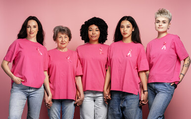 Women holding hands wearing pink ribbons for breast cancer awareness