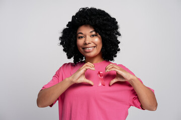 Young woman making heart shape with hands for breast cancer awareness