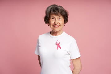 Senior woman smiling and wearing pink ribbon for breast cancer awareness