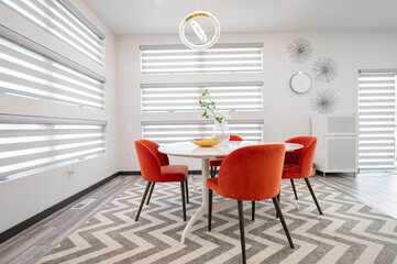 Modern dining area with orange chairs and striped blinds