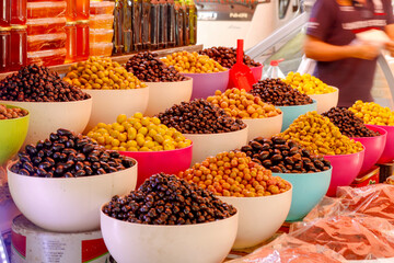 marinated olives in cups at farmers market with vendor in blur