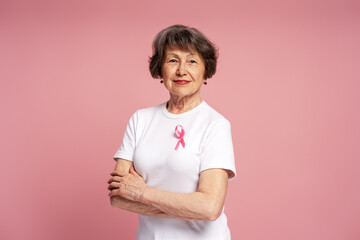Senior woman with pink ribbon supporting breast cancer awareness campaign
