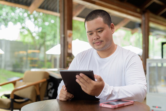 Asian plus size happy man sitting in cafe restaurant