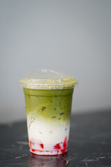 Close up and selective focus glass of iced matcha latte in coffee shop.