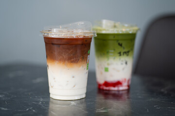 Close up glass of ice matcha green tea with jelly, iced latte on black marble table of a coffee shop summer terrace, menu photography.