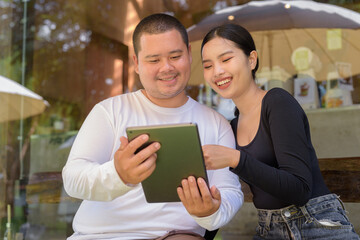 Couple sitting and using digital tablet computer in cafe