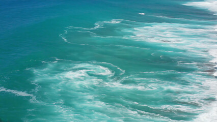 Aerial view of the ocean with turquoise water and white foam, showcasing the beauty and power of nature.