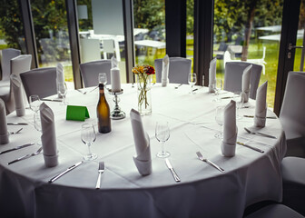 Elegant round table setup for a formal event with wine, candles, and floral centerpiece. Perfect...