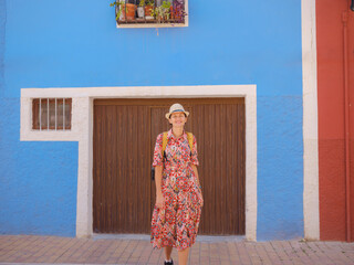 Woman in dress strolls through colorful streets of coastal town of La Vila Joiosa or Villajoyosa....