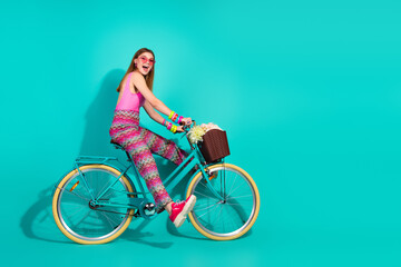 Young girl riding a teal bicycle against a turquoise background showcasing vibrant summer fashion...