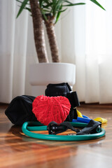 Heart-shaped yarn and fitness items representing the benefits of exercise for the heart, on World Heart Day. Vertical. Copy space.
