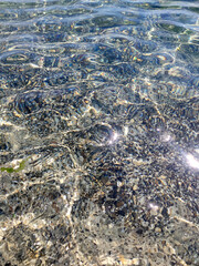Sun glare reflects off the crystal clear, transparent coastal sea water