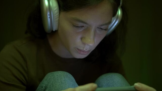 Teen playing game on smartphone sitting inside cardboard box, deprived of adult attention. Cardboard box as symbol of her world