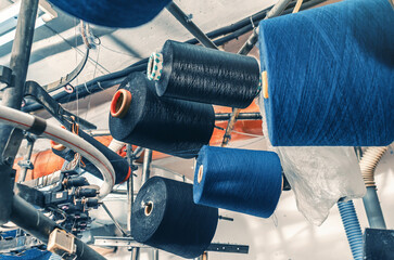 Colored threads on spools on machines. Industrial enterprise for production of socks. Modern...