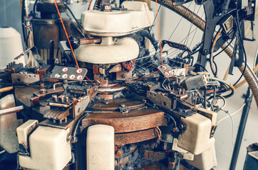 Rear view of knitting machine with cotton yarn in sock factory. Knitting machine with dust from...