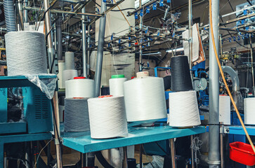 White gray and black threads on spools on machines. Industrial enterprise for the production of...