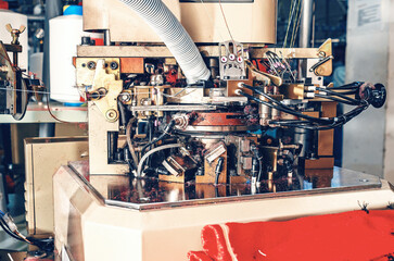 Close-up photo of machine in workshop with exhaust pipe on industrial knitting machine. Knitting...