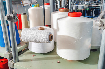 White threads on spools on machines. Industrial enterprise for the production of socks. Modern...