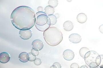 Abstract close up of iridescent soap bubbles floating against a bright white sky
