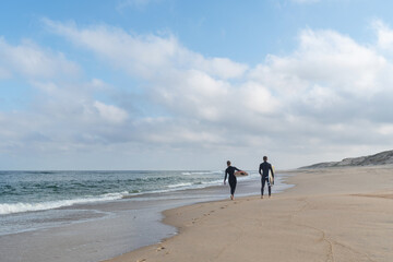 A couple of surfers walking along a natural beach in Les Landes