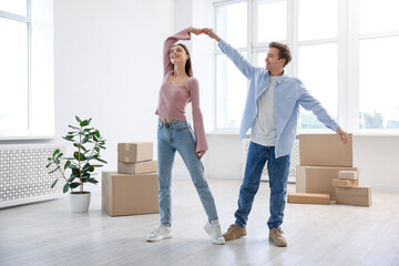 Happy young couple dancing and cardboard boxes at home. Moving day