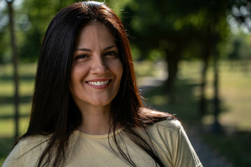 Portrait of beautiful smiling woman outdoors with sunlight behind her, enjoying happiness and warm...