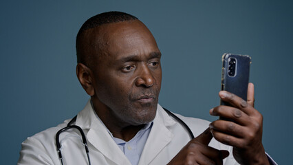 African American man male doctor in white uniform typing answer sending email message on smartphone...