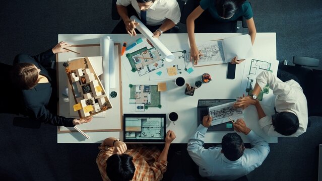 Group of diverse team planning strategy while sitting at table with project plan. Top aerial view of smart business people working together to brainstorm and design house construction. Alimentation.