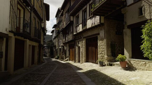 Sunlit street in Mogarraz, famed for portraits on fa&ccedil;ades and rustic architecture. Great for cultural, travel, and heritage visuals.