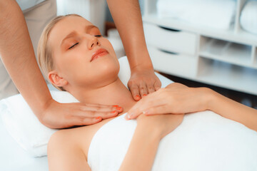 Caucasian woman customer enjoying relaxing anti-stress spa massage and pampering with beauty skin recreation leisure in day light ambient salon spa at luxury resort or hotel. Quiescent