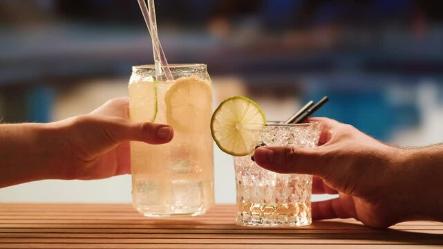 Fruit cocktail in hotel bar, Two cocktail glasses cheers in the hands on sea background. Bartenter making drink in bar, Summer vacation concept, A beautiful couple enjoy the vacation at the beach.