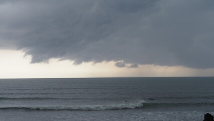Obraz premium A powerful storm with dark clouds and dramatic waves approaches the coastline at sunset