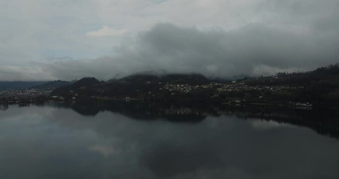 Aerial view of Lake Lugano with mountain peaks and clouds, Switzerland.
