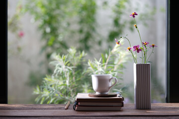 White ceramic coffee cup and delicate pink flowers in a white vase