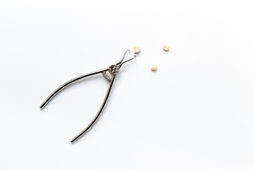 Teeth crows for implantation with dental tooth extraction forceps on white background. Professional Dentist desktop, top view