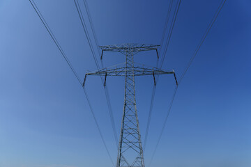 High-voltage power line tower against clear blue sky