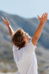 Young man practicing yoga and raising arms in the mountains