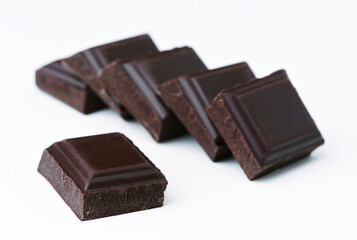 Dark chocolate pieces creating delicious composition on white background